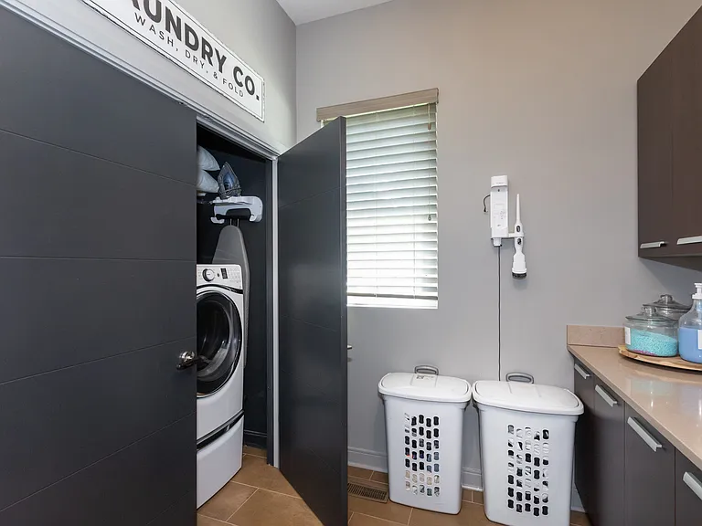 Spacious laundry room equipped with lot of storage space.