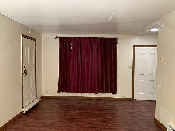 Very decent sized living room with double curtains to keep cold air out. New baseboard heater at lower right. New low wattage LED light fixture over door, and all through apartment. Door to left goes to "dead space" storage area that goes with front unit.
