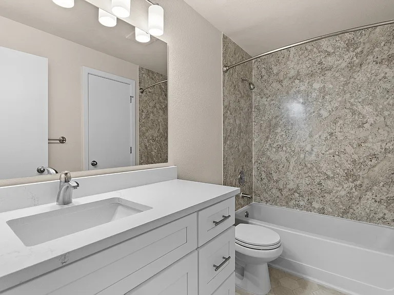 A bright, updated bathroom with a spacious vanity, modern finishes, and a full bathtub with a decorative shower surround. A bright, updated bathroom with a spacious vanity, modern finishes, and a full bathtub with a decorative shower surround.