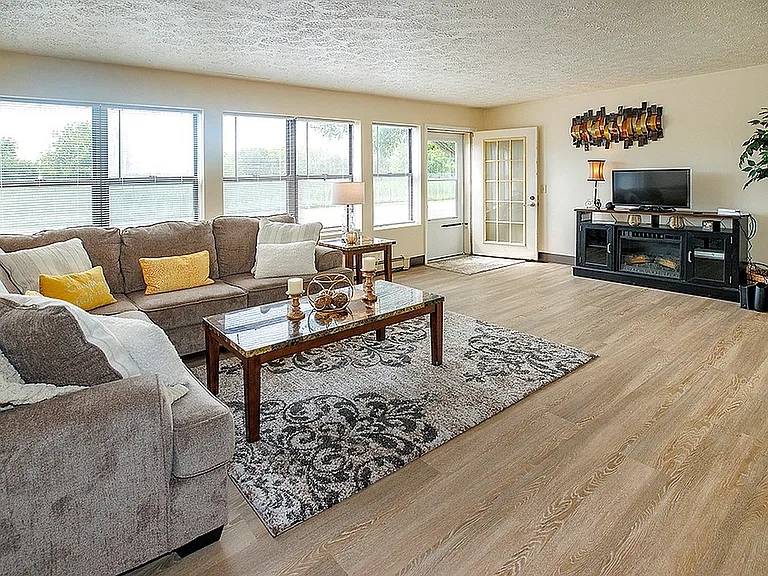 Bright and spacious living room featuring a cozy sectional sofa, large windows, and stylish decor, creating a welcoming and modern atmosphere.