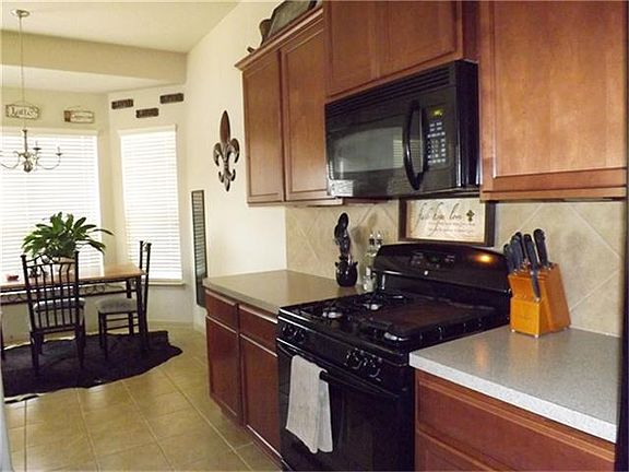 Black appliances, dark cabinets, tile backsplash and laminate countertops.