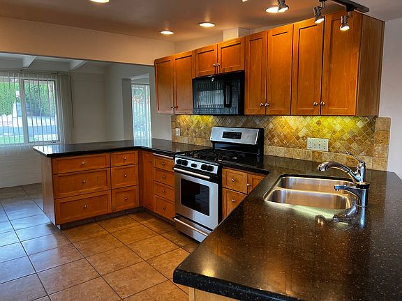 The custom kitchen features ample counter space, a counter-height breakfast bar and barstools, as well as a range, dishwasher, refrigerator, and microwave.