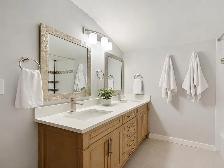 Updated bath with a double-sink vanity, ample cabinet storage, and a tiled tub/shower with contemporary fixtures.