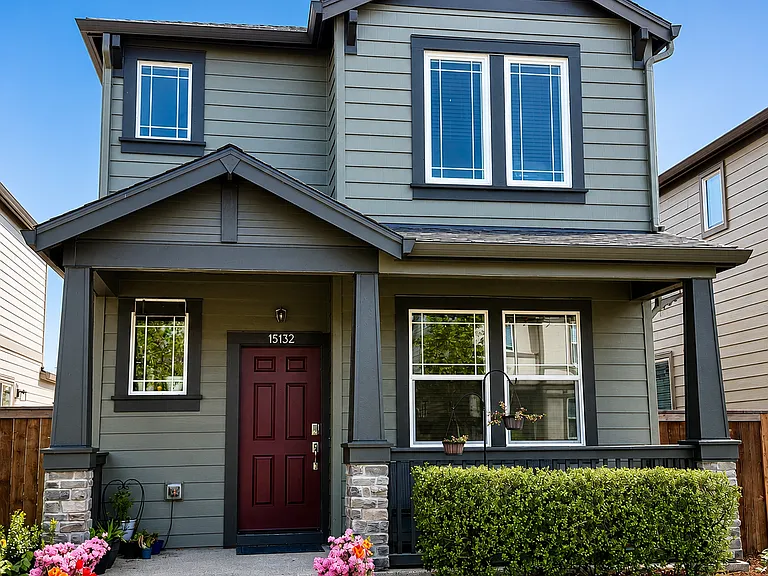 Modern two_story home with keypad + manual_lock main door, covered patio, and a well_maintained front yard featuring shrubs, flowers, and a clean walkway.