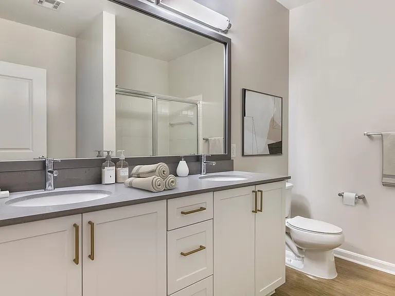 Renovated Package II bath with grey quartz countertops, white cabinetry, and hard surface flooring