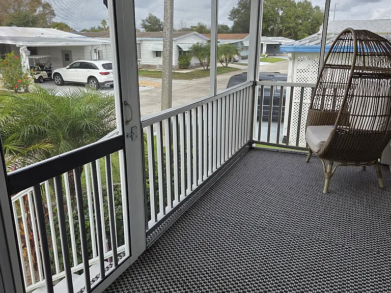 Welcoming enclosed carpeted patio with ceiling fan