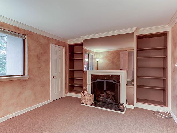 Den with wood fireplace and built-in bookshelves