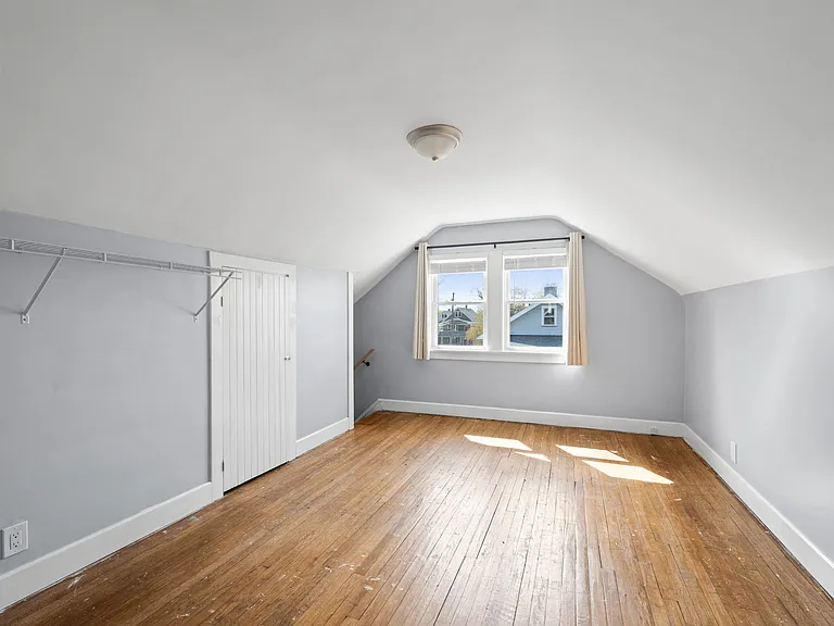 This is the smaller room on the third floor, second level of the unit. It has some closet racking and shows the storage area, as well as the steps that lead down to the back entrance of the unit.