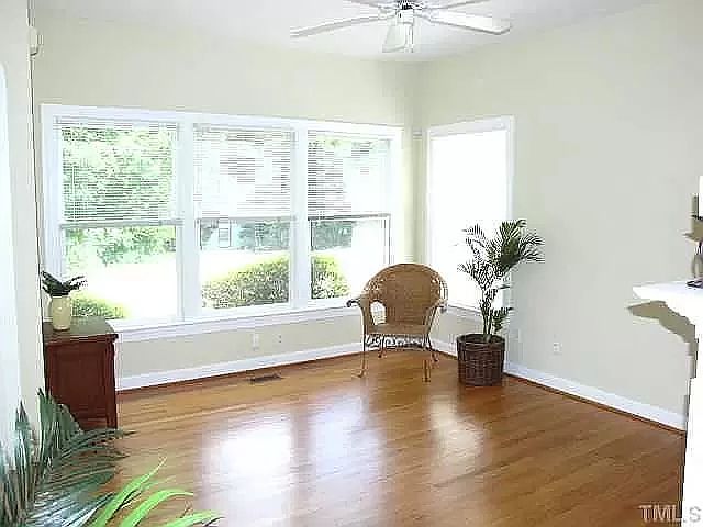 Family room has great windows, wood floors and a ceiling fan.
