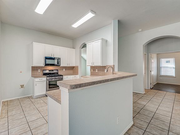 Kitchen featuring white cabinetry, a built-in microwave, stainless steel range, and a breakfast bar with an integrated sink