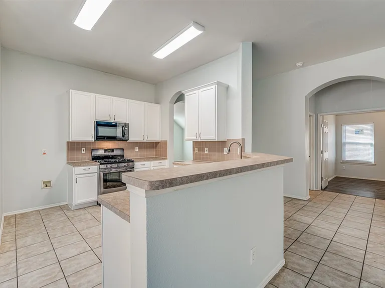 Kitchen featuring white cabinetry, a built-in microwave, stainless steel range, and a breakfast bar with an integrated sink
