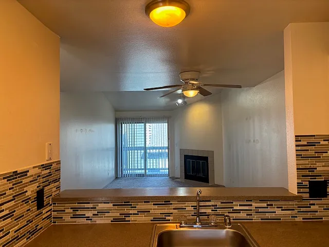 View from kitchen in upgraded unit, into open concept dining and living area. Tiled backsplash in foreground.