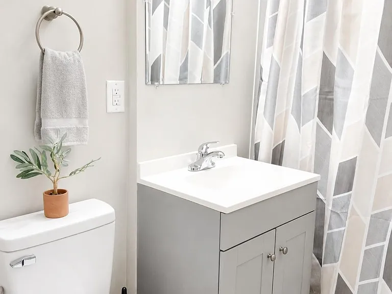 Clean full bath with gray vanity, ample under-sink storage, and a tub/shower combo with curtain and wall mirror.