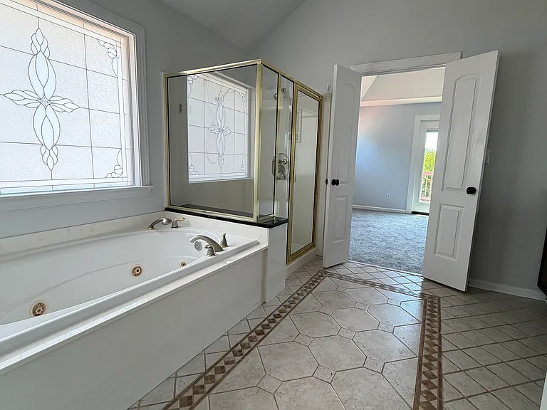 En-suite master bathroom with a soaking tub, natural light and spacious tile flooring_unwind with a quiet soak after a day on the lake.