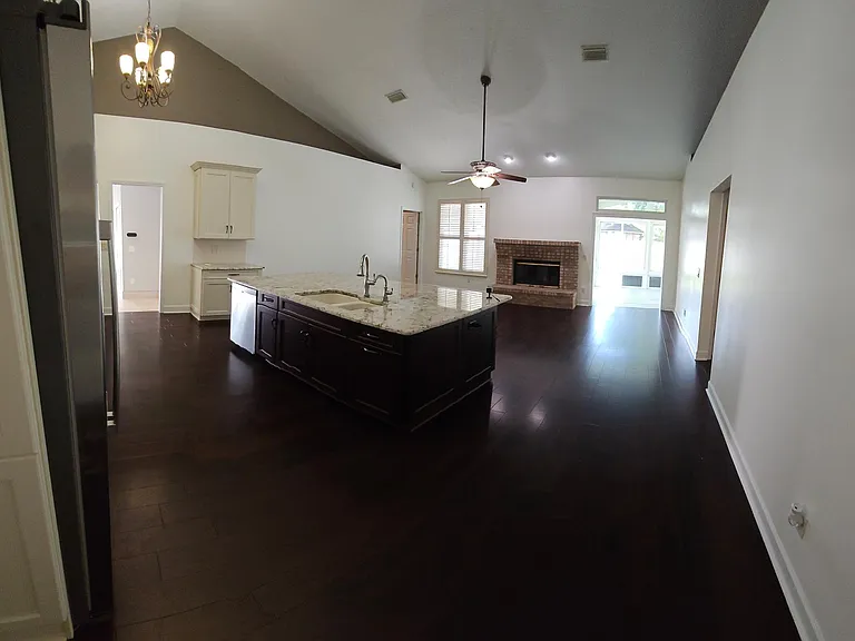 Kitchen with large island and custom countertop overhang. Wood fireplace. Mahogany flooring.