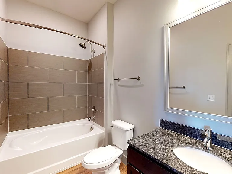 Apartment bathroom with large soaking tub and wood-style flooring.