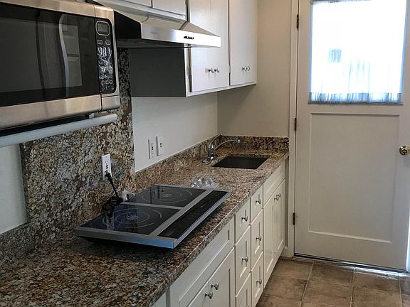 new granite kitchen!! and chandelier with newer lower cabinets for storage. Microwave, hotplate stove, high volume fan included only with brand new Farberware dishwasher on countertop next to sink.