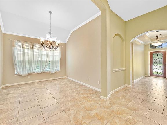 Charming formal dining room with crown moulding, beautiful chandelier, and tile flooring. Art niches and rounded corners throughout.