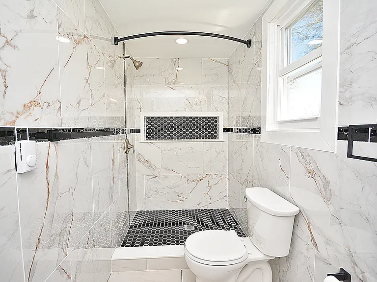 Newly renovated modern bathroom with tiled walls.