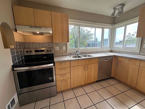 Stainless steel appliances with IKEA cabinets and shelving.