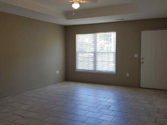 Living room front window & door. Tile floors and ceiling fan.