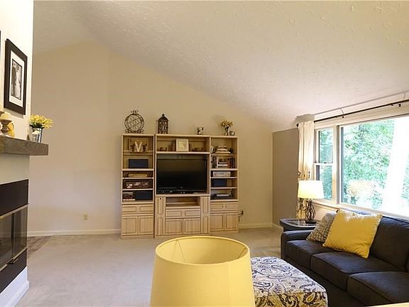 Living room with 3 way gas fireplace, vaulted ceiling, and newer carpeting