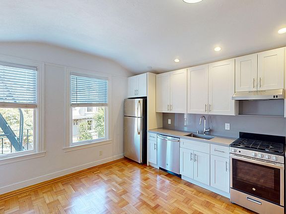 Kitchen with multiple cabinets, refrigerator, stove, range hood, and sink