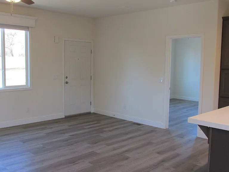 Living room area showing entry door and a look into the master bedroom.