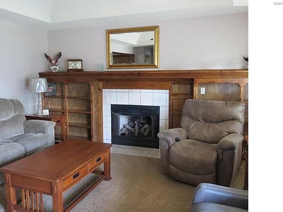 Great room has built in bookshelves around fireplace. Vaulted ceiling with fan and light.