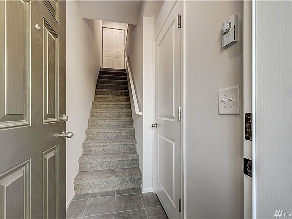 Entrance with garage door to right and coat closet with bench at top of stairs