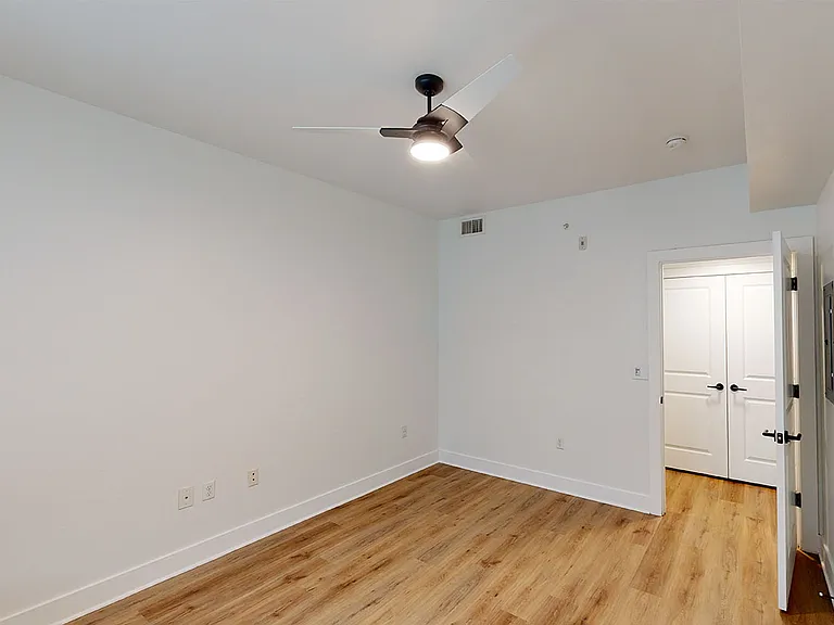 Spacious apartment bedroom with wood-style flooring.