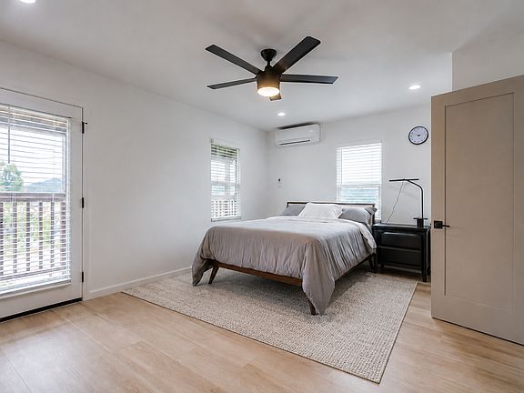Spacious primary bedroom featuring a king-size bed, dedicated workspace, walk-in closet, and direct access to the private balcony.