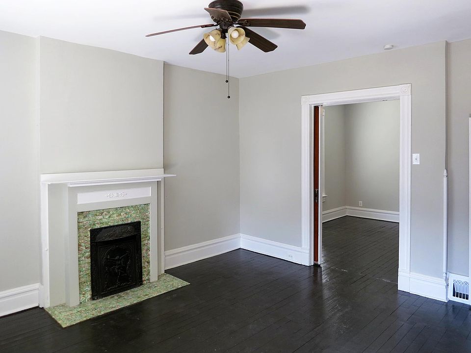 Gorgeous original fireplace in the living room and a ceiling fan light fixture.