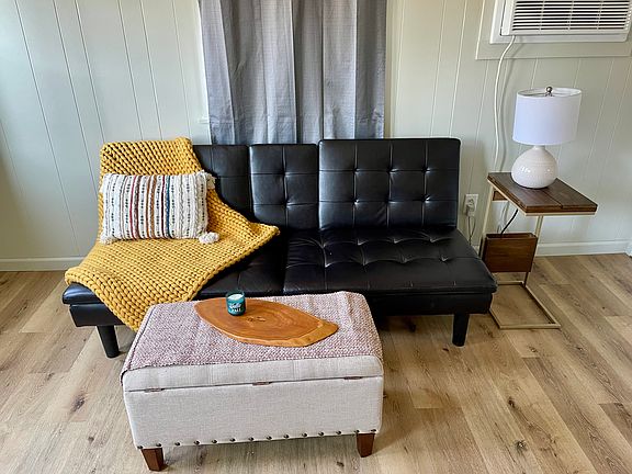 Living area. Furniture included or can be removed if not needed. Decor not included. Notice new flooring and fresh paint! Curtains included.