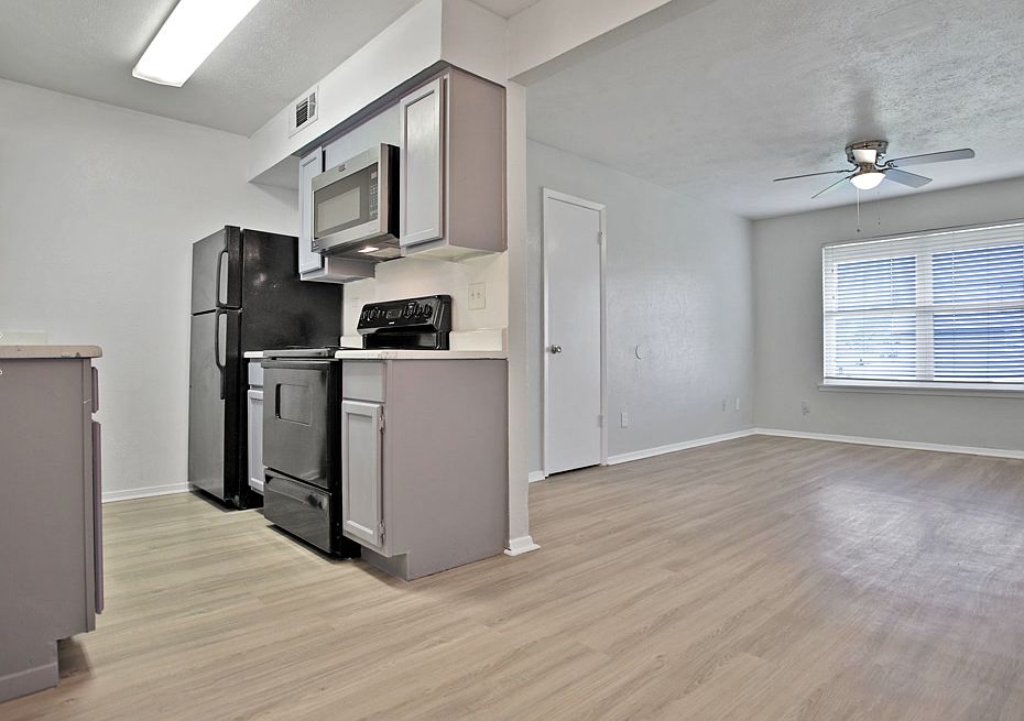 Kitchen with black appliances, white cabinets, and wood-style flooring