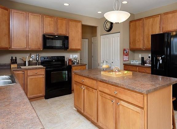 Large open kitchen, 42" maple cabinets, breakfast bar, double pantry and black appliances open to the main floor laundry