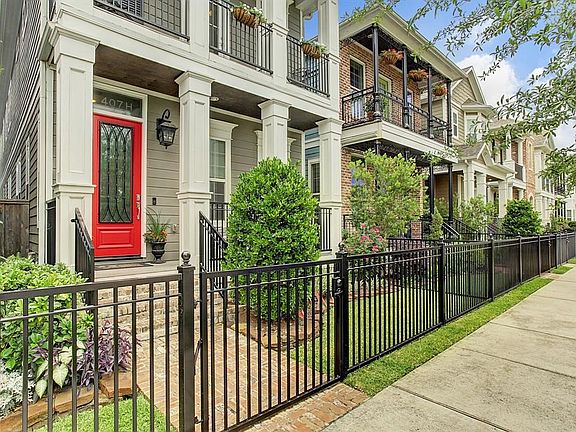 The front yard dazzles with the lush landscaping and stunning red door.
