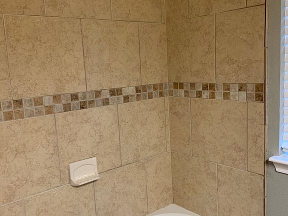 Hall bath features ceramic tile surround, custom cabinets & countertop