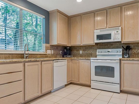 Open Kitchen has granite counters, stainless sink and faucet, generous cabinet storage and large window with wooded views.
