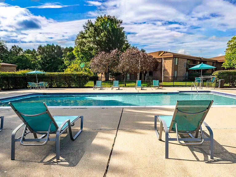 Heated pool equipped with comfy lounge chairs at Westwood Village Apartments in Westland, MI