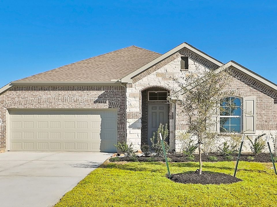 Experience elegance with a stately brick and stone facade, arched doorway, and manicured lawn at Riv