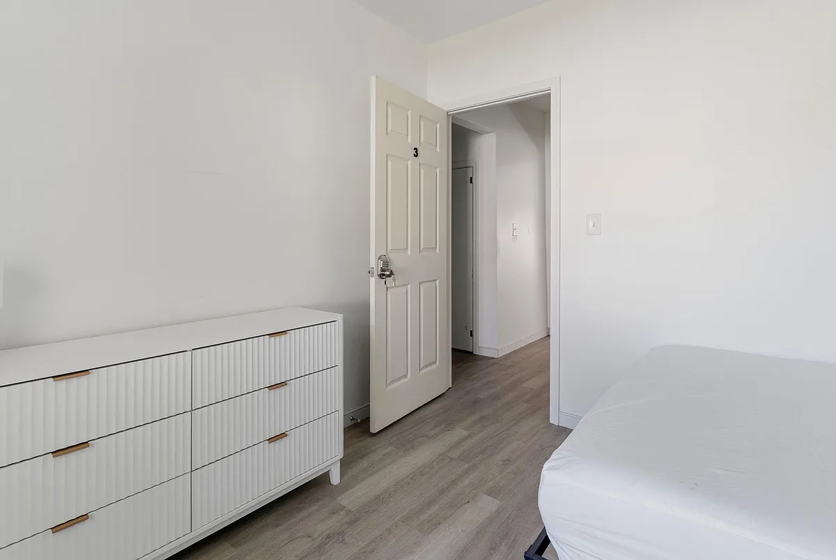 Bedroom features durable wood-look flooring, a dresser for storage, and an easy-access layout with entry to the hall. - S South St