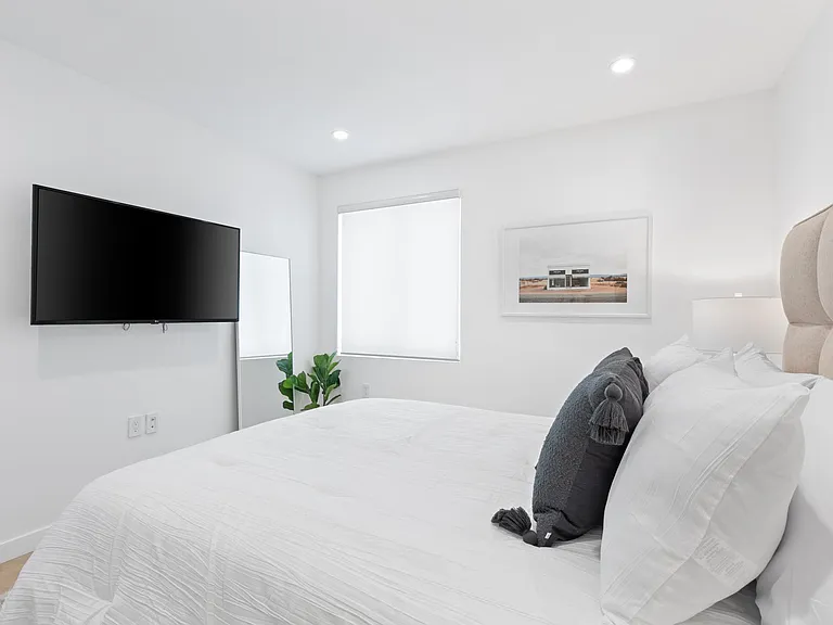 Relax in the upstairs master bedroom, featuring a smart tv and comfortable bed.