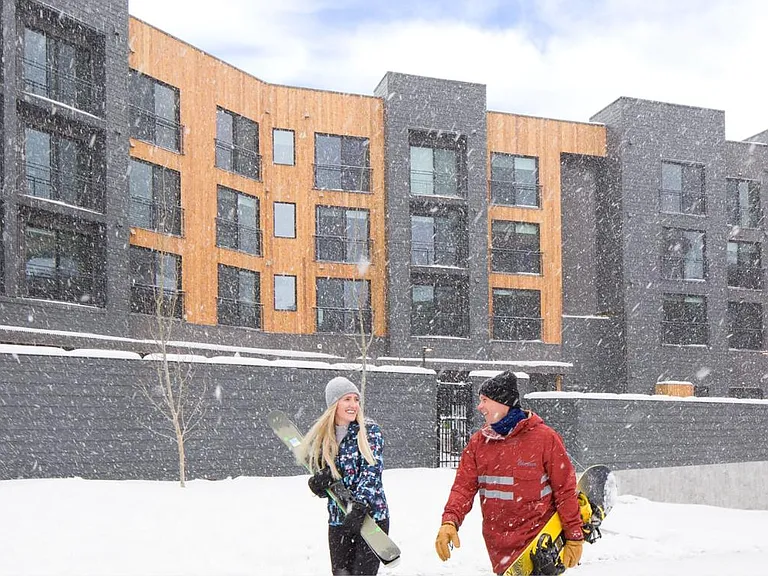 Canyon Haus snowy exterior with couple walking to the lifts.