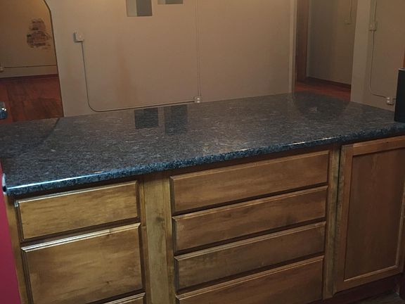 Large granite breakfast counter with industrial lighting.