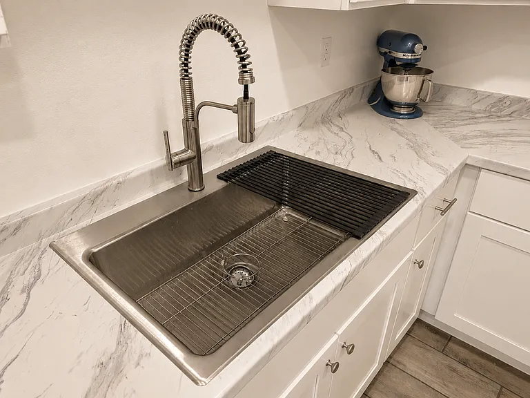 Chef's corner: Extra-deep, commercial-grade stainless steel workstation sink complete with a premium Kohler pull-down professional spring faucet and built-in drying rack.