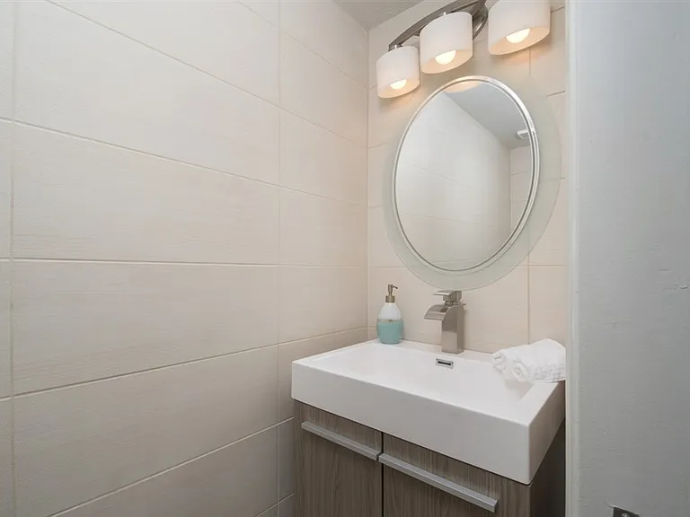 This stylish powder room, nestled within a 1000sqft condominium, offers a modern and inviting ambiance.