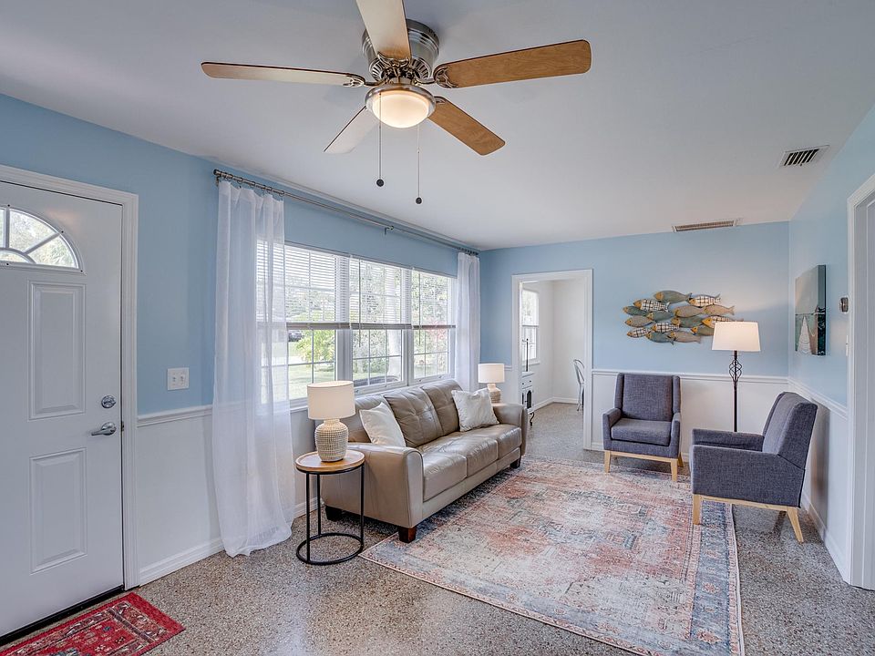 Furnished spacious living room with large picture windows, terrazzo floor and ceiling fan