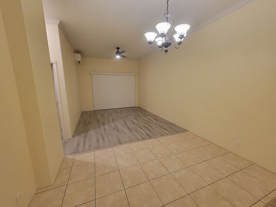 tiled dining area and hard-wood-looking living room with split a/c unit, ceiling fan, chandelier, and large sliding door to step out to the lanai and front yard