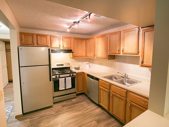 Upgraded kitchens with silver appliances and wood-style floo